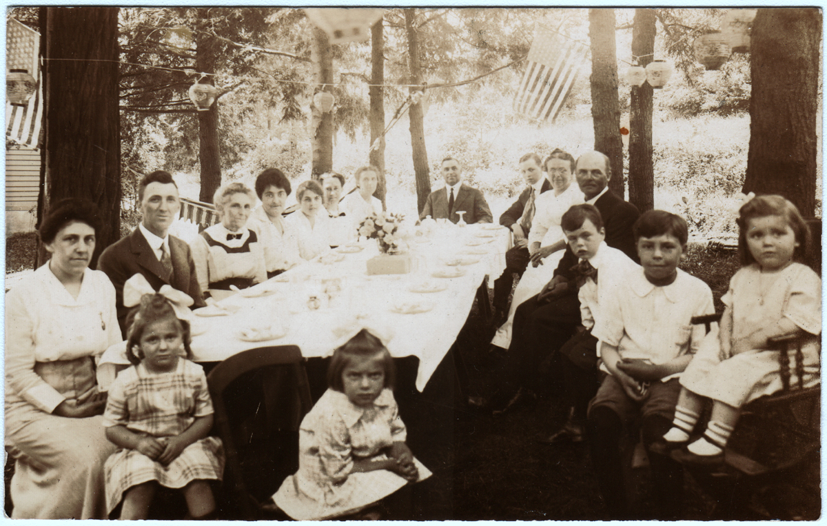Scan of photo in possession of Linda (Funk) Shook, on the back of a postcard (unused). Move the cursor over the image to see the name of each individual. Click on a person to open the page for that person.
Gladys (Troup) Stickler had a copy of the same photo which probably was in Marion DeVoe's possession when she died in 1986, and was sent to Gladys by Frank Kenneth DeVoe. Note on the reverse of Gladys's copy: probably taken around 1918.
F. K. DeVoe identified the persons in the photo and said it was a 4th of July picnic at the Anderson House on Post Road, White Plains.